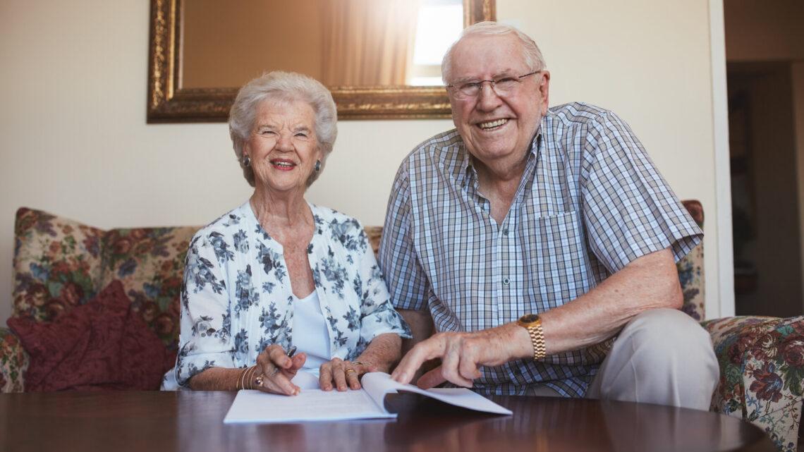 Lächelndes Rentnerehepaar beim Durchsehen von Dokumenten