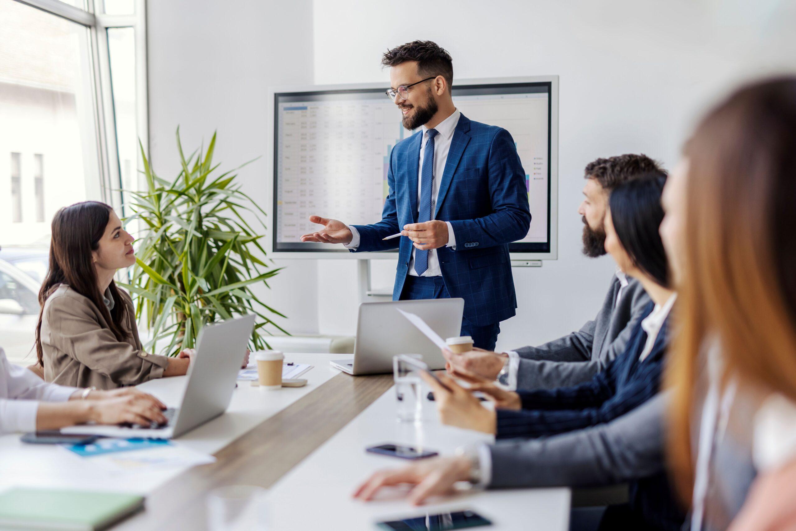 Compliance E Learning: Führungskraft stärkt Vertrauen im Team durch offene Kommunikation und Schulung im Konferenzraum