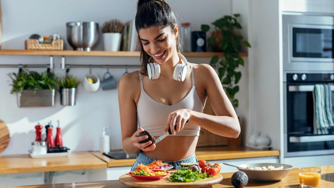 Fit Woman bereitet eine gesunde Poké-Bowl in der Küche zu Hause zu.