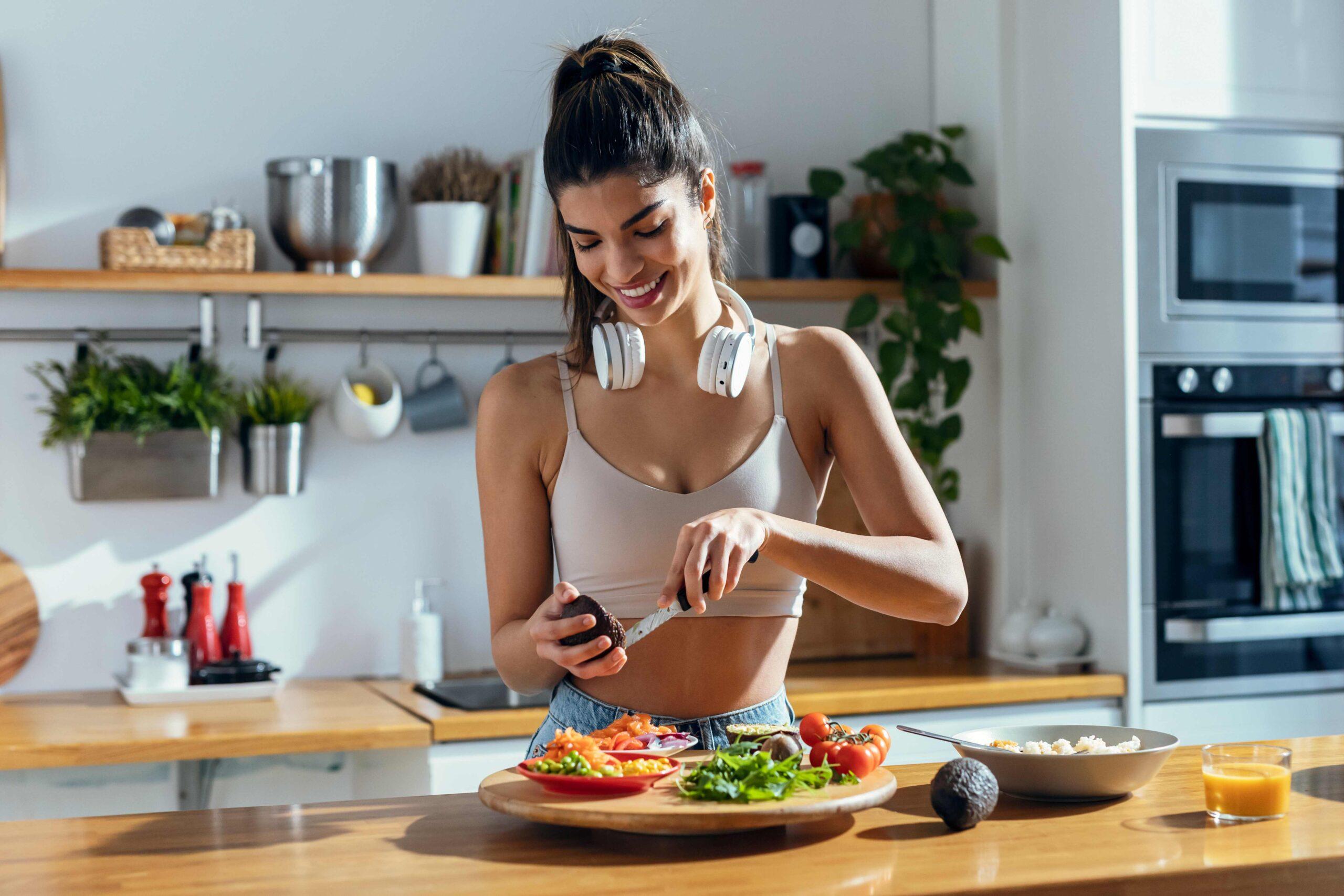 Fit Woman bereitet eine gesunde Poké-Bowl in der Küche zu Hause zu.